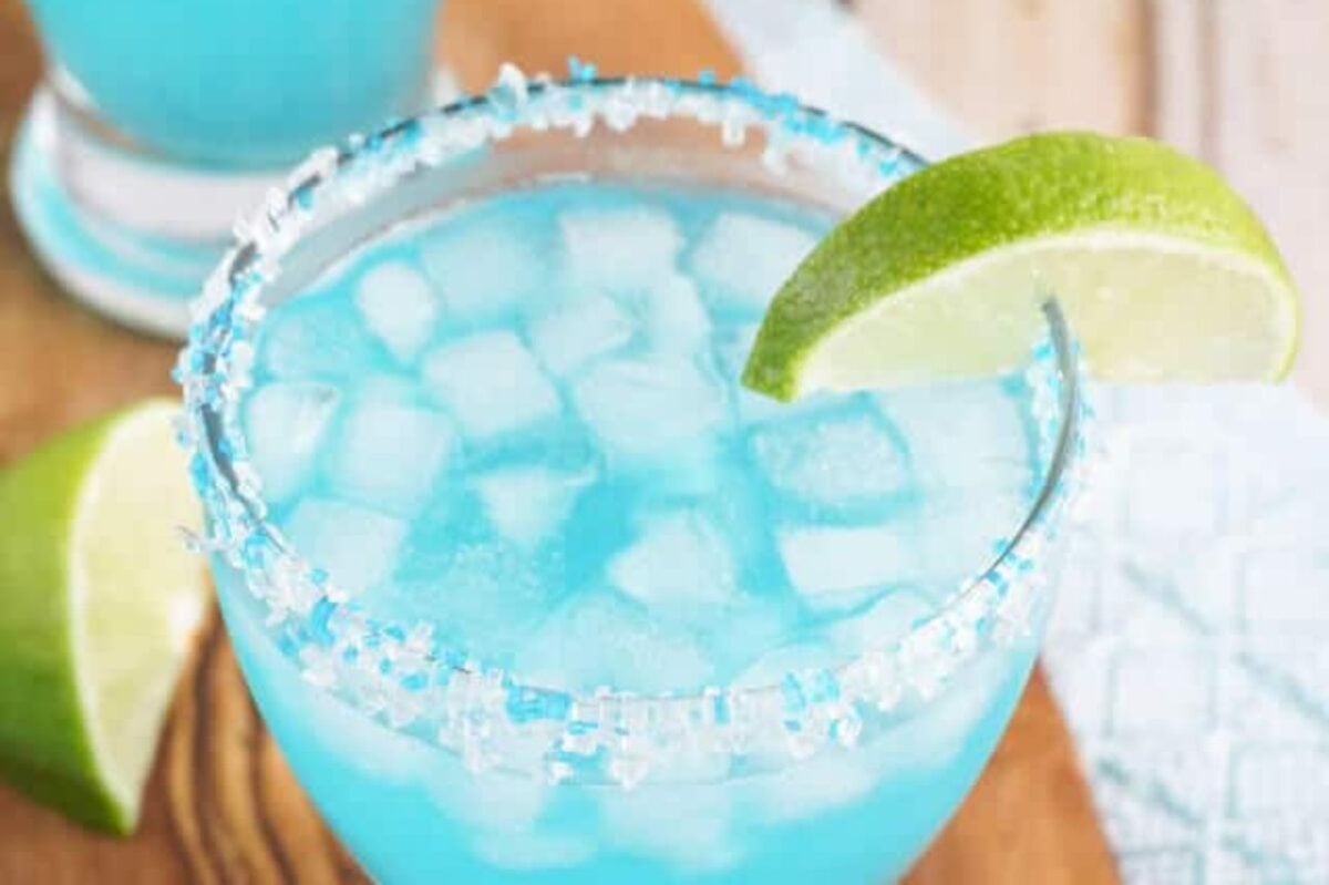 A blue margarita with lime garnish and a salted rim on a wooden surface, perfect for Easter cocktails.