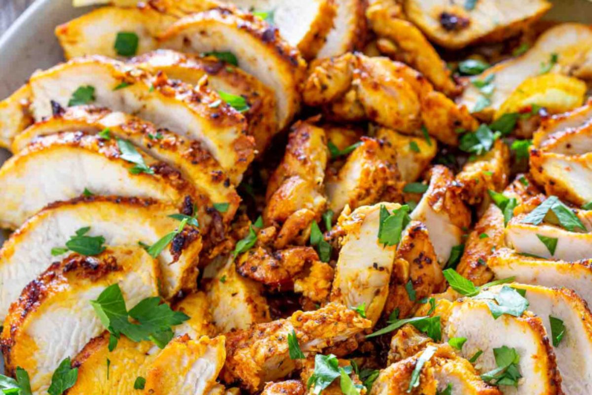 Sliced, grilled chicken breast garnished with fresh chopped parsley.