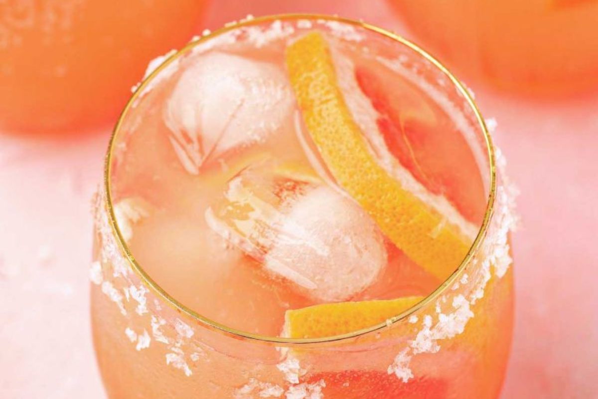 A close-up of a cold Easter cocktail with ice cubes and a citrus garnish in a glass with a salted rim.
