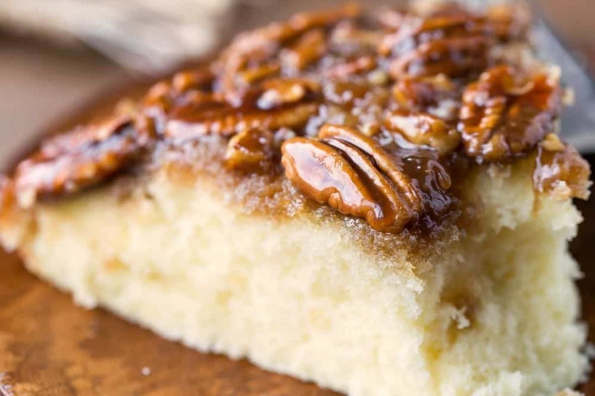 A close-up of a slice of moist upside down cake topped with caramelized pecans.