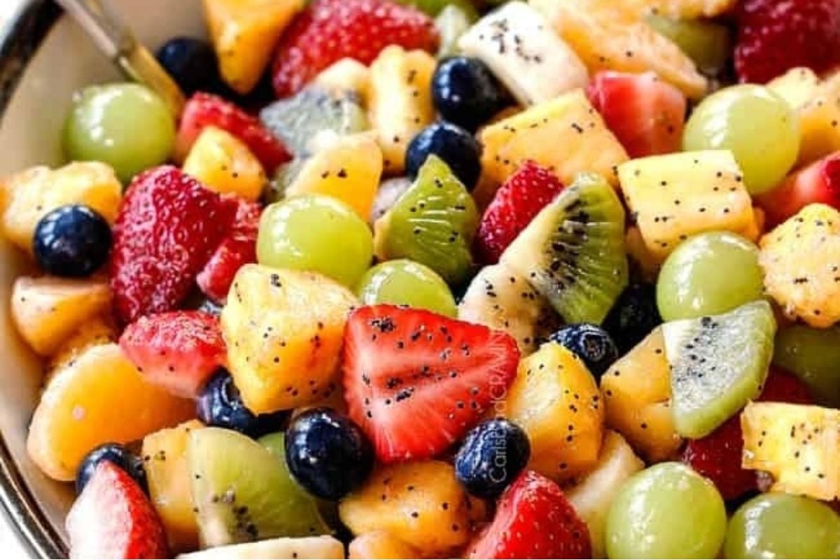 A bowl of fruit salad with pomegranate seeds, perfect for potluck sides.