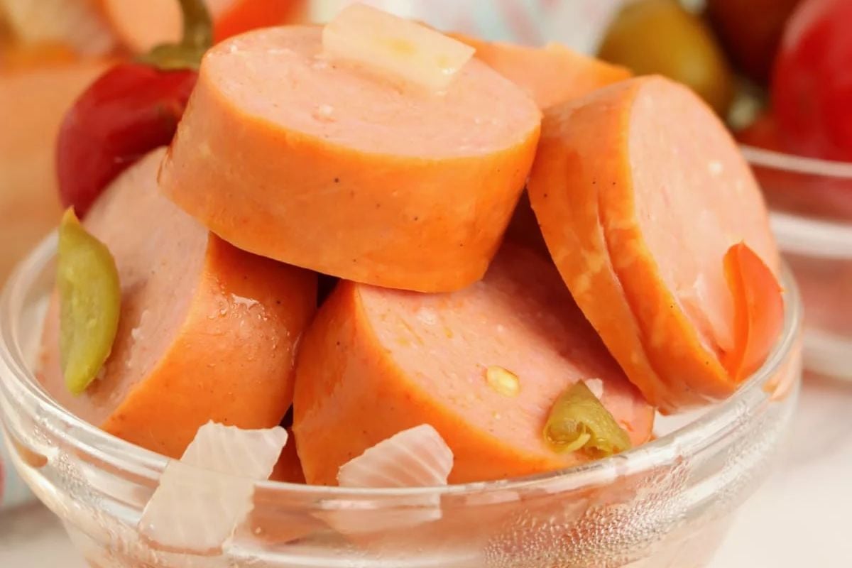 Sliced sausage with pieces of green olives and onions in pickled recipes.