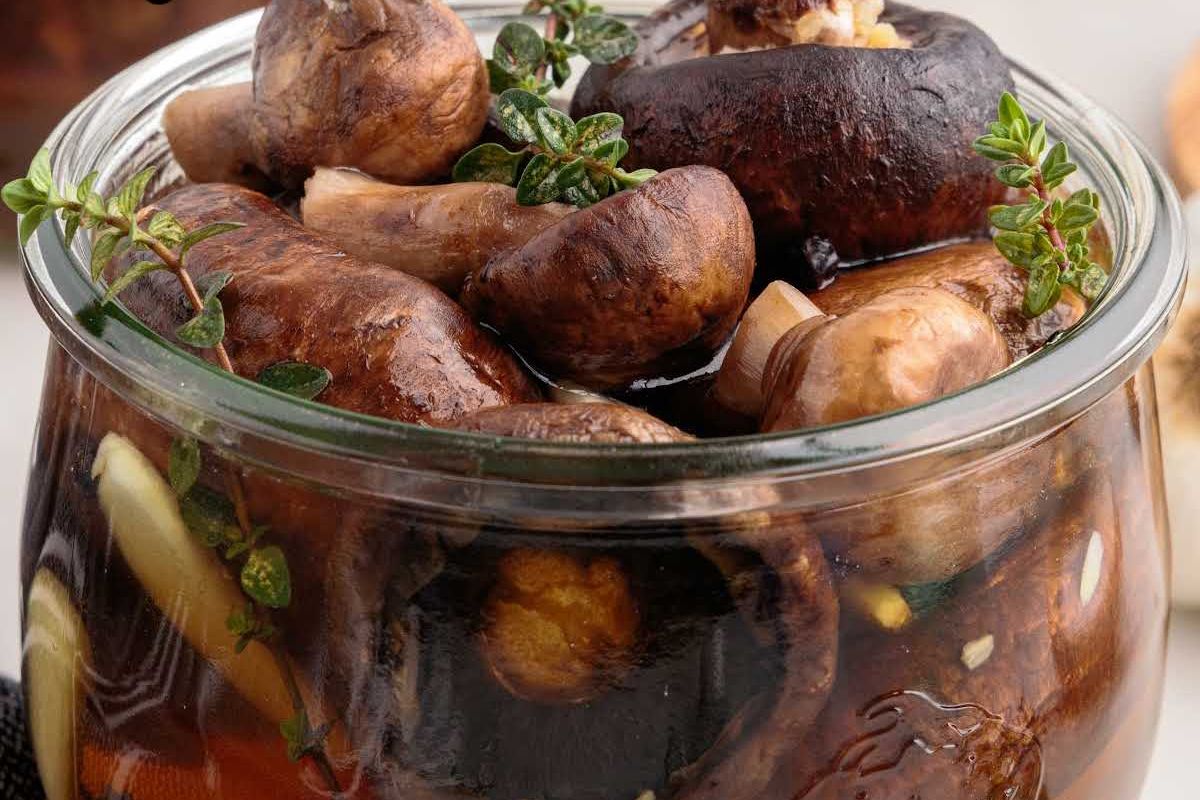Jar of assorted pickled mushrooms garnished with fresh herbs, perfect for Easter sides.