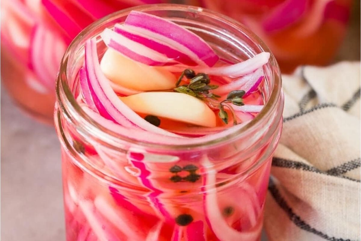 A jar of pickled red onions and spices for pickled recipes.