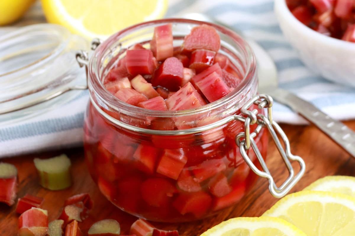 A jar of pickled rhubarb from pickled recipes with lemon slices in the background.