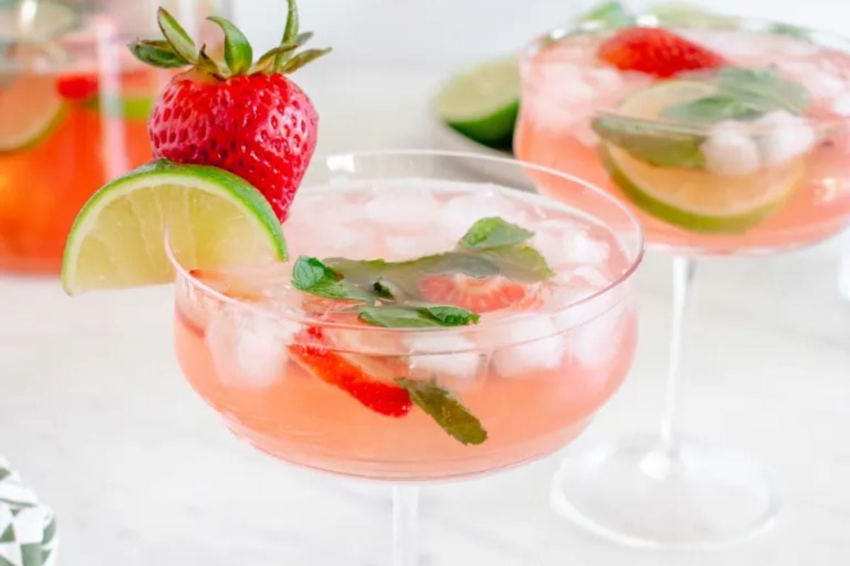Two Easter strawberry cocktails garnished with lime and mint leaves, served in stem glasses.