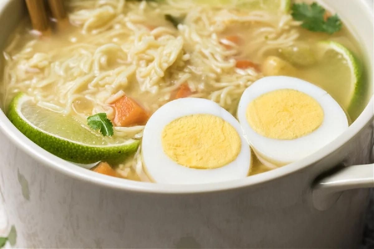 A bowl of chicken noodle soup recipes with an egg on top.