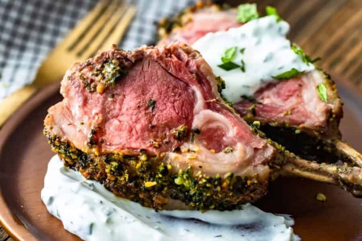 Easter dinner herb-crusted rack of lamb served with a creamy sauce.