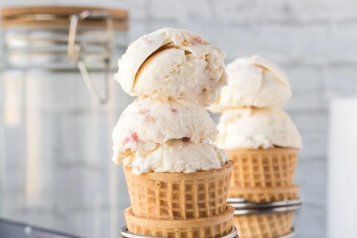 Three scoops of strawberry-rhubarb ice cream in a waffle cone.