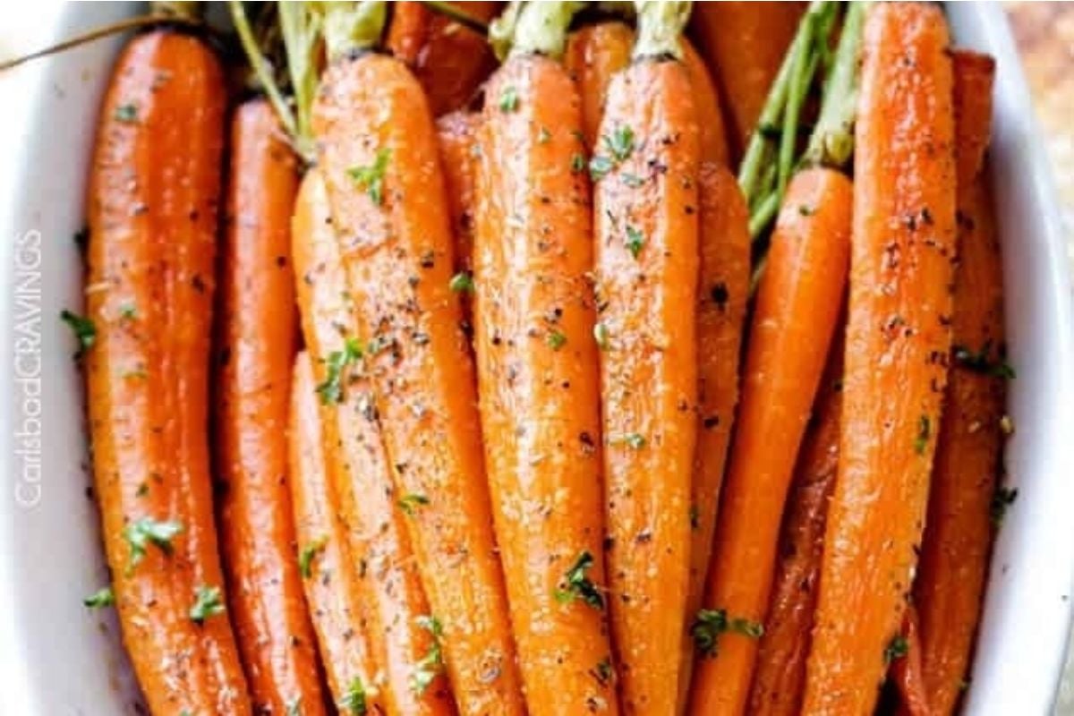 Roasted carrots in a white dish with herbs, perfect for potluck sides.