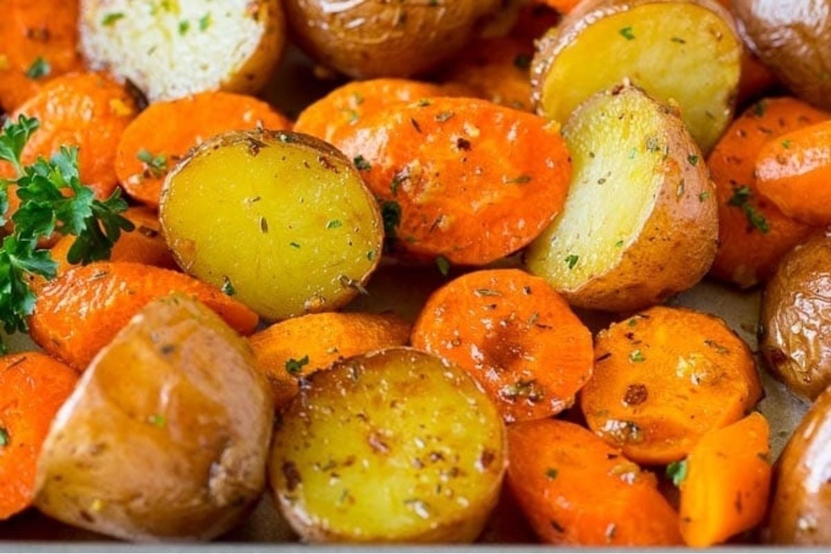 Roasted carrots and potatoes on a baking sheet, perfect for potluck sides.