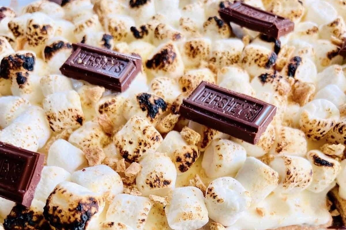 A s'mores pizza with chocolate bars and marshmallows, perfect for potluck desserts.