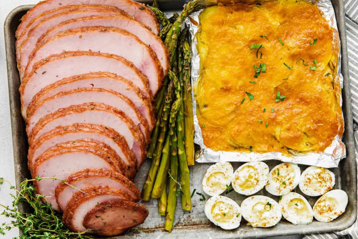 An Easter dinner tray with sliced ham, asparagus, a casserole, and deviled eggs.