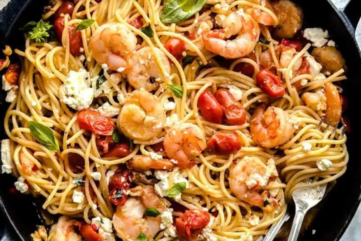 A plate of shrimp pasta from our seafood recipes with tomatoes, garlic, and basil, garnished with crumbled cheese.