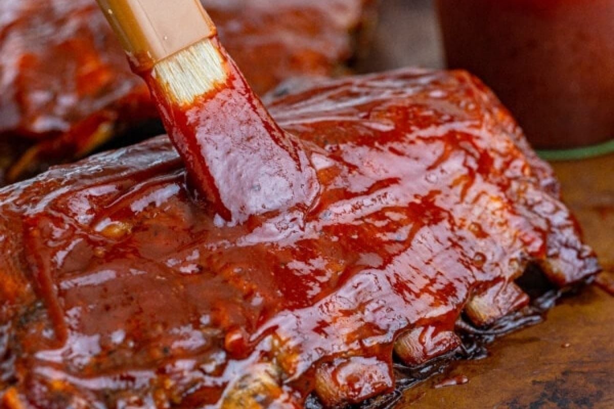 Slow cooker recipes for BBQ ribs being dipped in BBQ sauce.