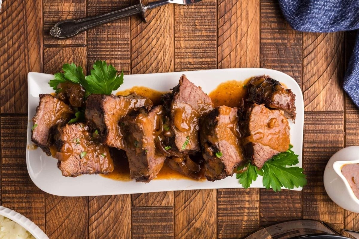 A plate of slow cooker meat with sauce and parsley.