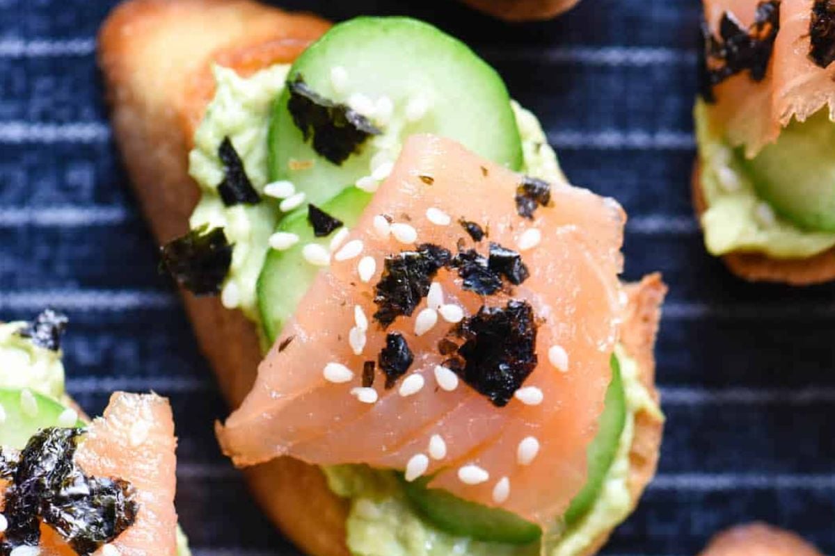 Close-up of an Easter appetizer featuring smoked salmon and avocado toast garnished with sesame seeds and seaweed.