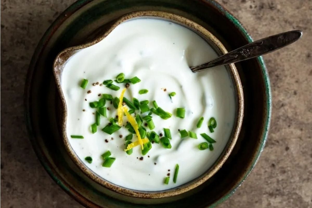 A bowl of sour cream with lemon and chives, perfect for potluck sides.