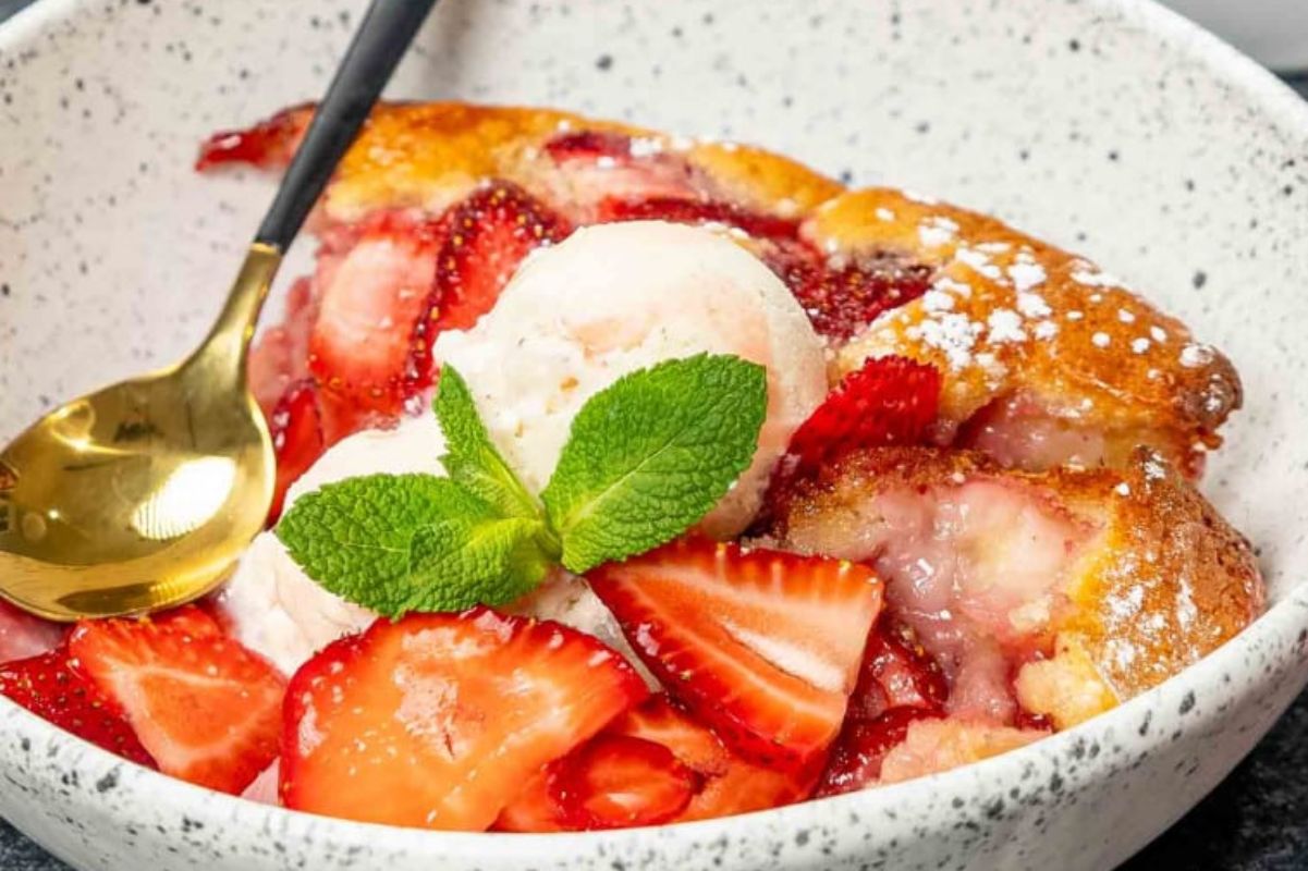An Easter bowl of strawberry dessert topped with a scoop of vanilla ice cream and garnished with fresh mint leaves.