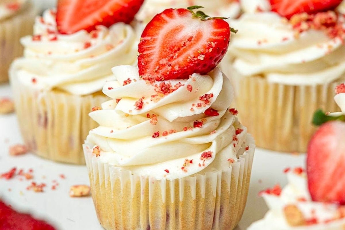 Strawberry cupcakes topped with whipped cream and strawberries, perfect for potluck desserts.