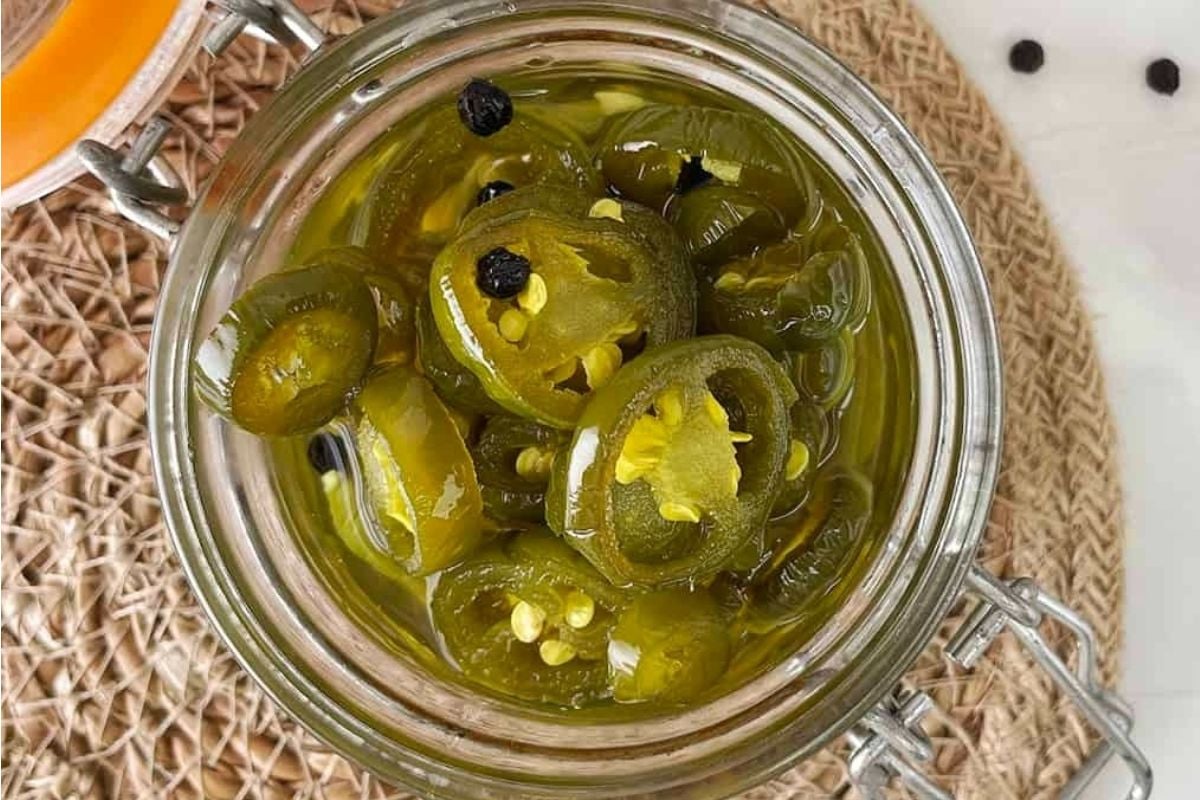 A jar of pickled jalapeños with visible spices, perfect for pickled recipes.