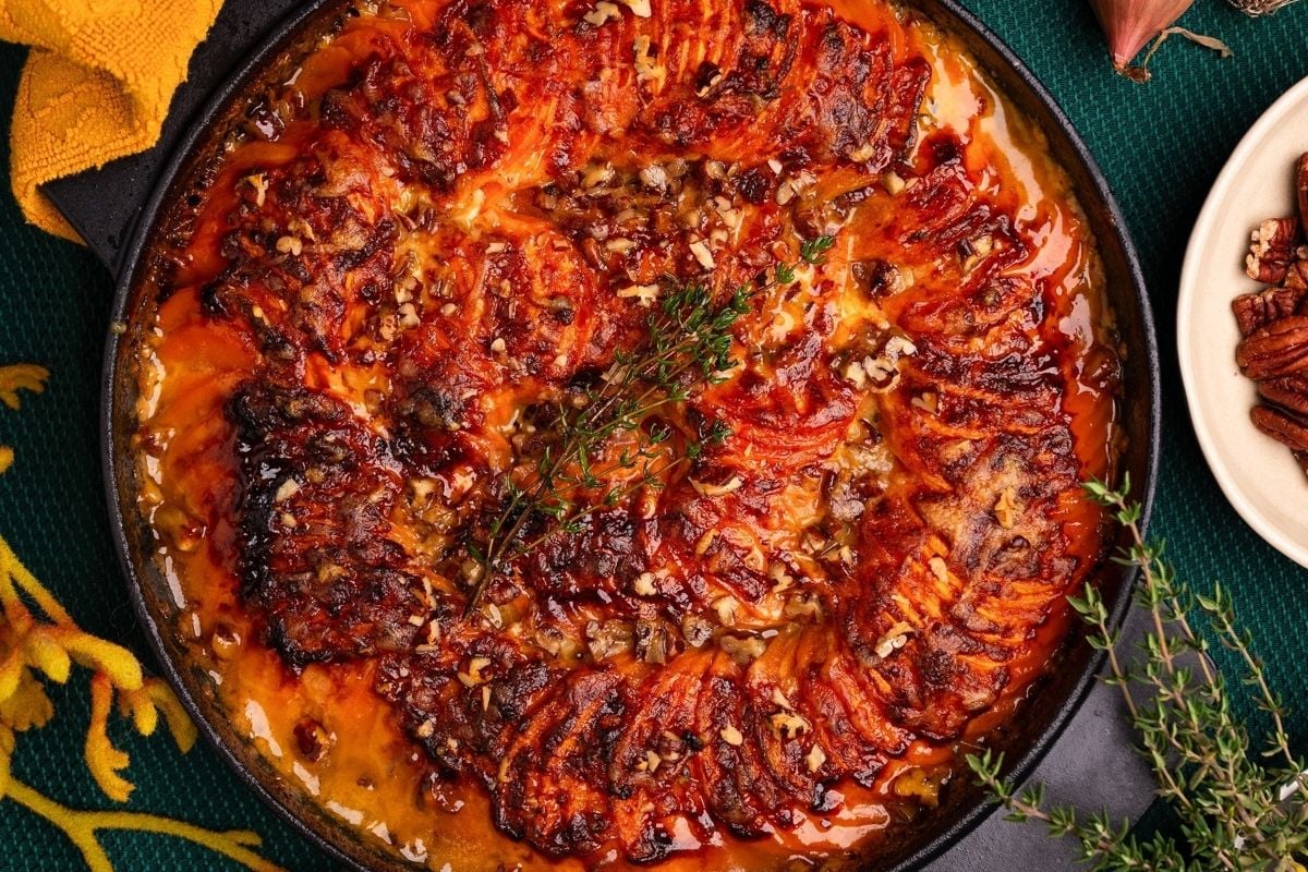 Baked sweet potatoes arranged in a spiral, topped with herbs, nuts, and a sprinkle of cheese for a twist on classic cheesy recipes.