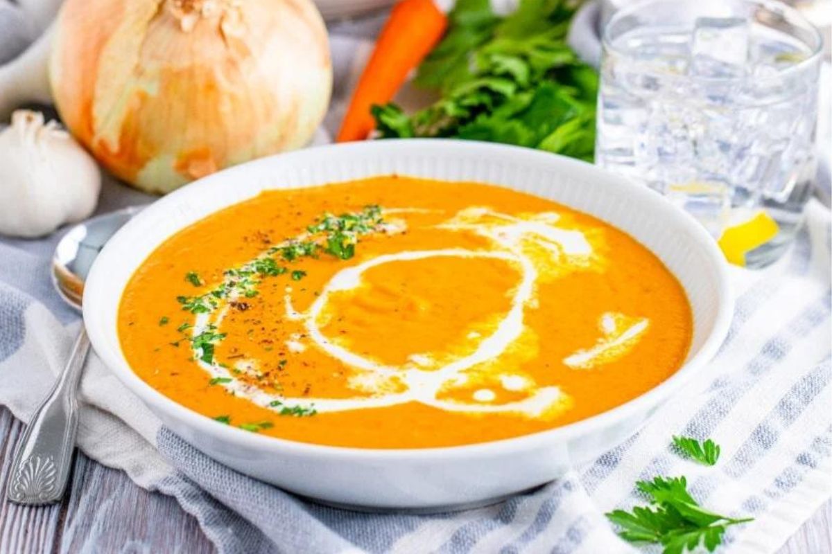 A bowl of carrot soup recipes with sour cream and parsley.