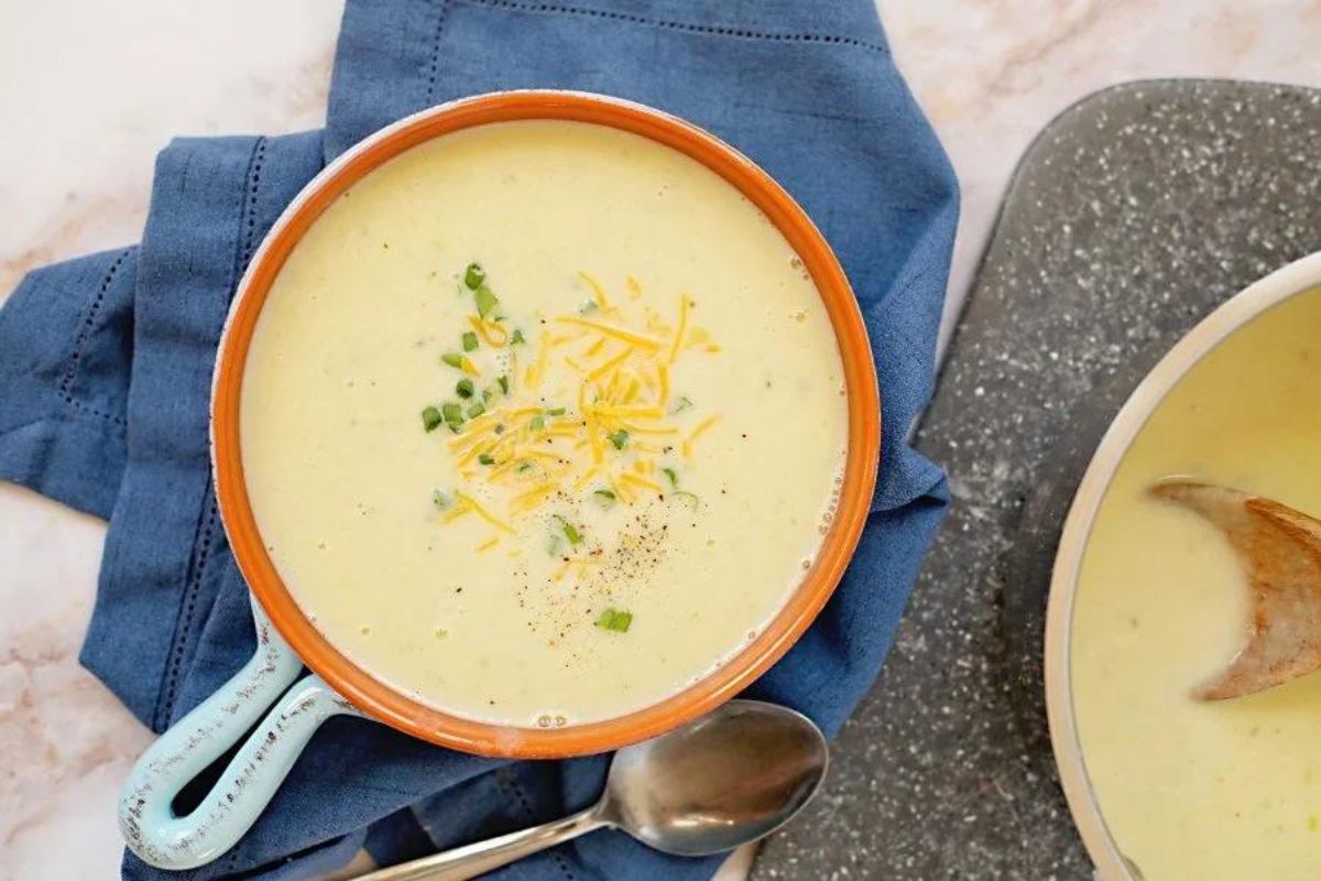 A bowl of cheesy potato soup recipes with a spoon.