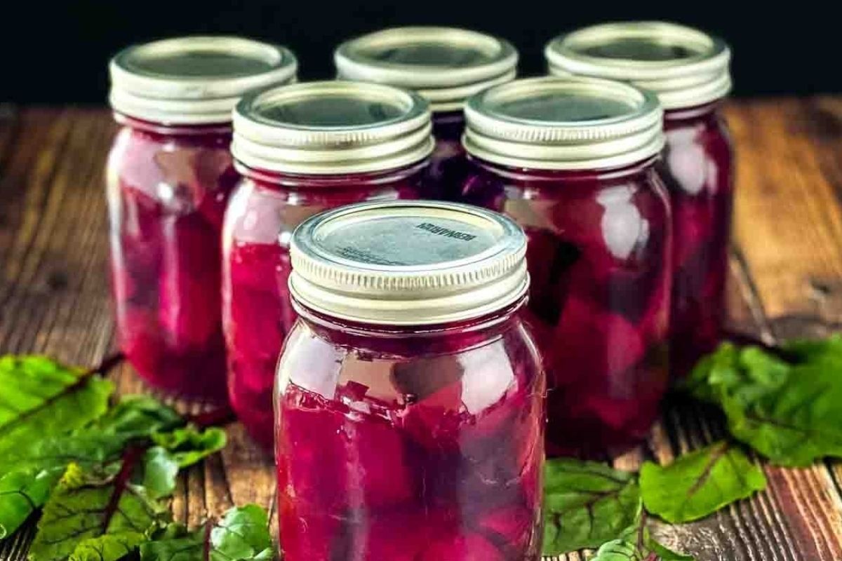 Jars of homemade pickled beets from pickled recipes on a wooden surface.