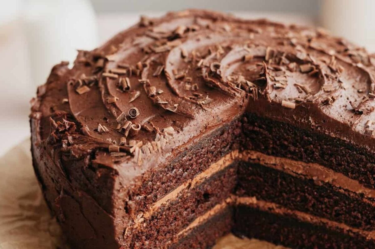A close-up of a chocolate layer cake with chocolate frosting and chocolate shavings on top.