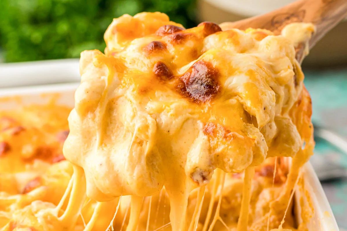 A serving of cheesy baked macaroni being lifted from a casserole dish, demonstrating its gooey texture, perfect for Easter dinner.