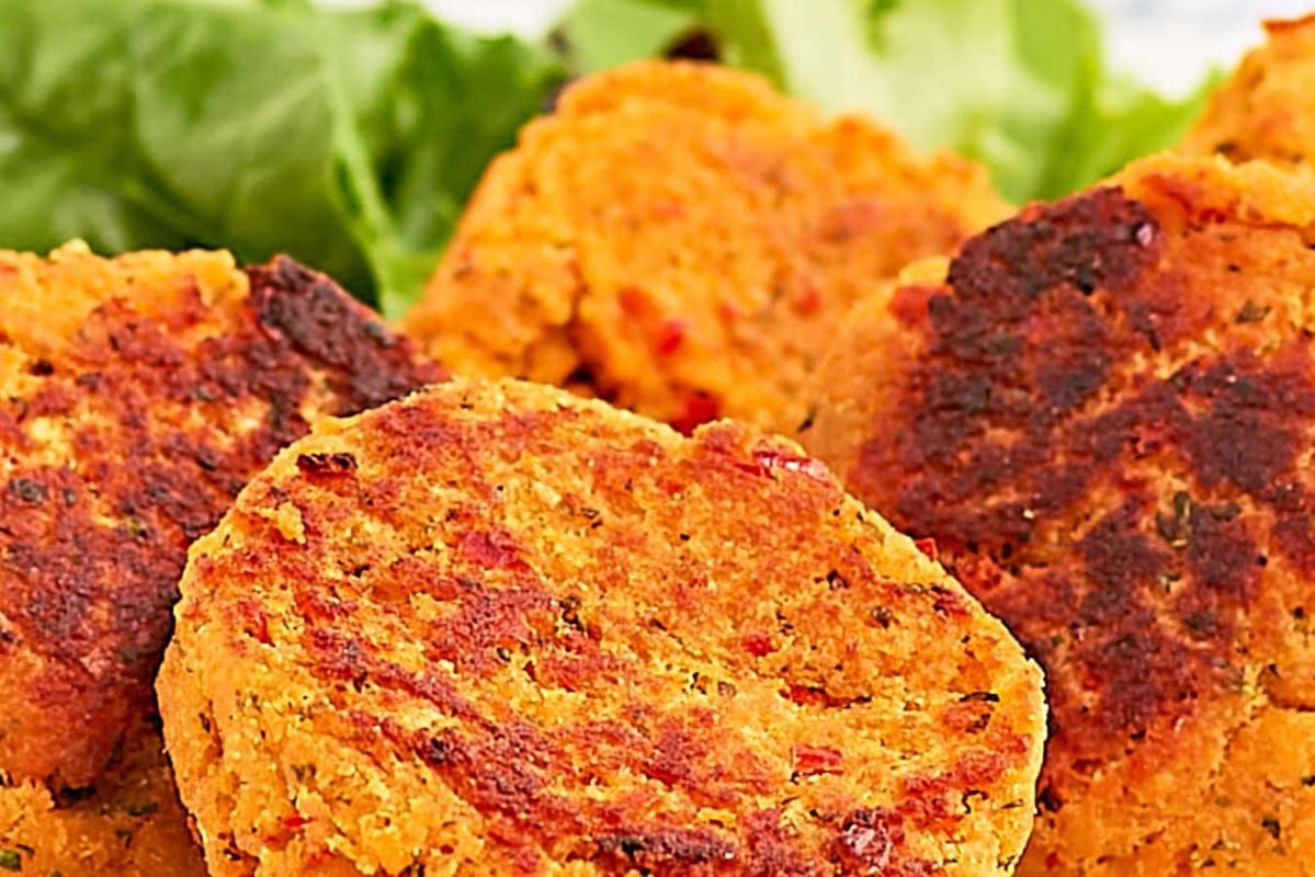 Close-up of vegan patties made with red and yellow vegetables, showing a crispy exterior and vibrant, textured interior inspired by seafood recipes.