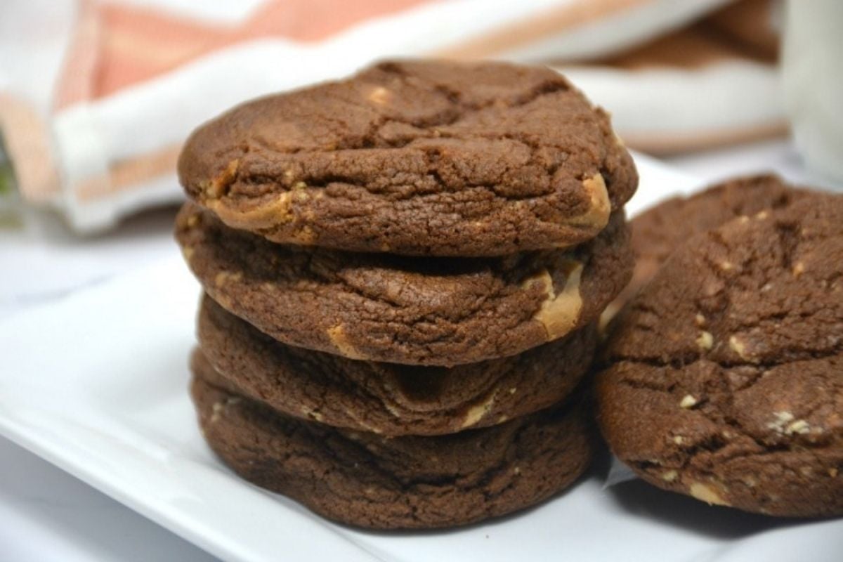 A stack of chocolate cookie recipes with peanut butter chips on a white plate.
