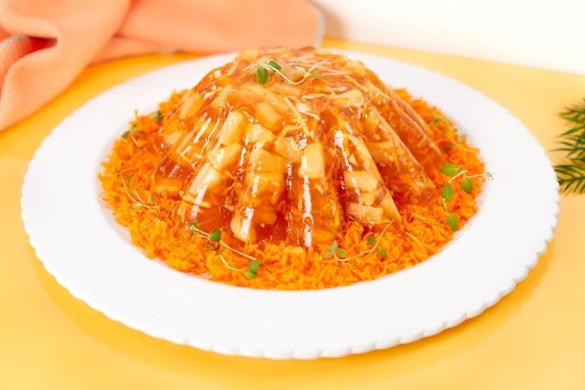 A plate with a dish of orange jello salads on it.