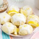 Italian lemon ricotta cookies that are topped with icing and lemon zest on a plate.