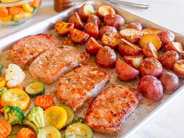 A tray of sheet pan honey garlic pork chops and vegetables, perfect for a quick sheet pan recipe.