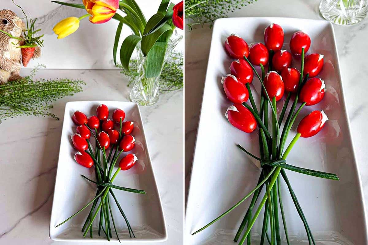 A creative Easter appetizer presentation of cherry tomatoes and chives arranged to resemble a bouquet of tulips on a white platter, alongside a floral arrangement with actual tulips.