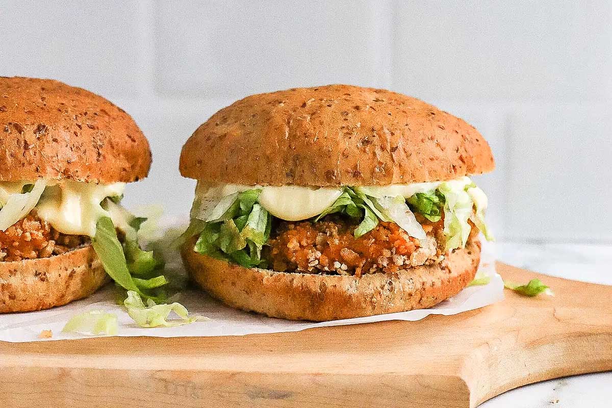 Two veggie burgers with lettuce and sauce on whole grain buns, inspired by McDonald's recipes, displayed on a wooden board.