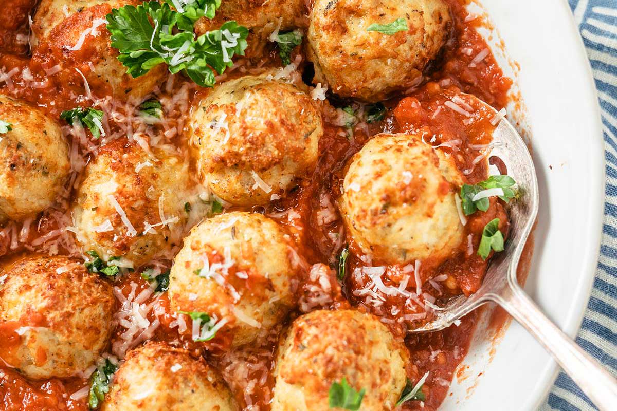 A plate of spaghetti and meatballs topped with marinara sauce, sprinkled with Parmesan cheese, and garnished with parsley, all made in 30 minutes or less.