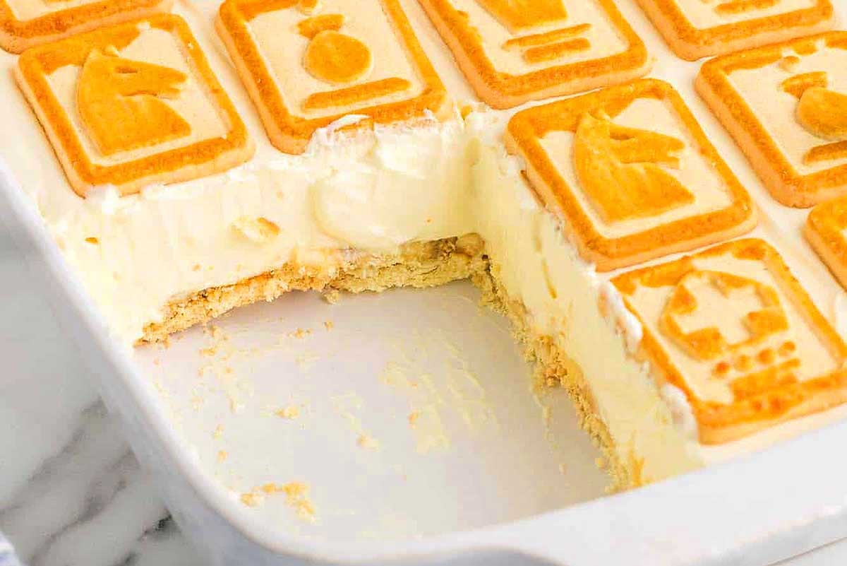 A tray of orange-flavored pudding mix cream bars with one piece partially removed.