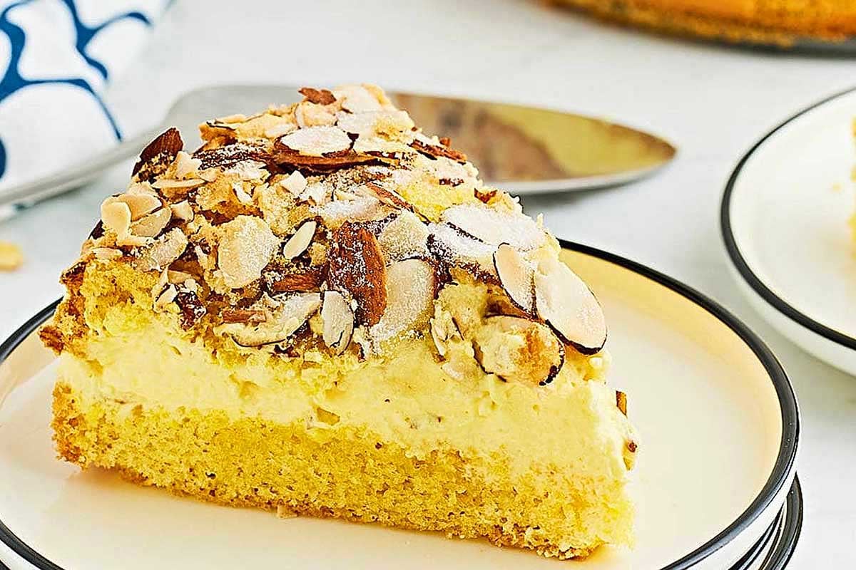 A slice of almond-topped cake made with pudding mix on a white plate.