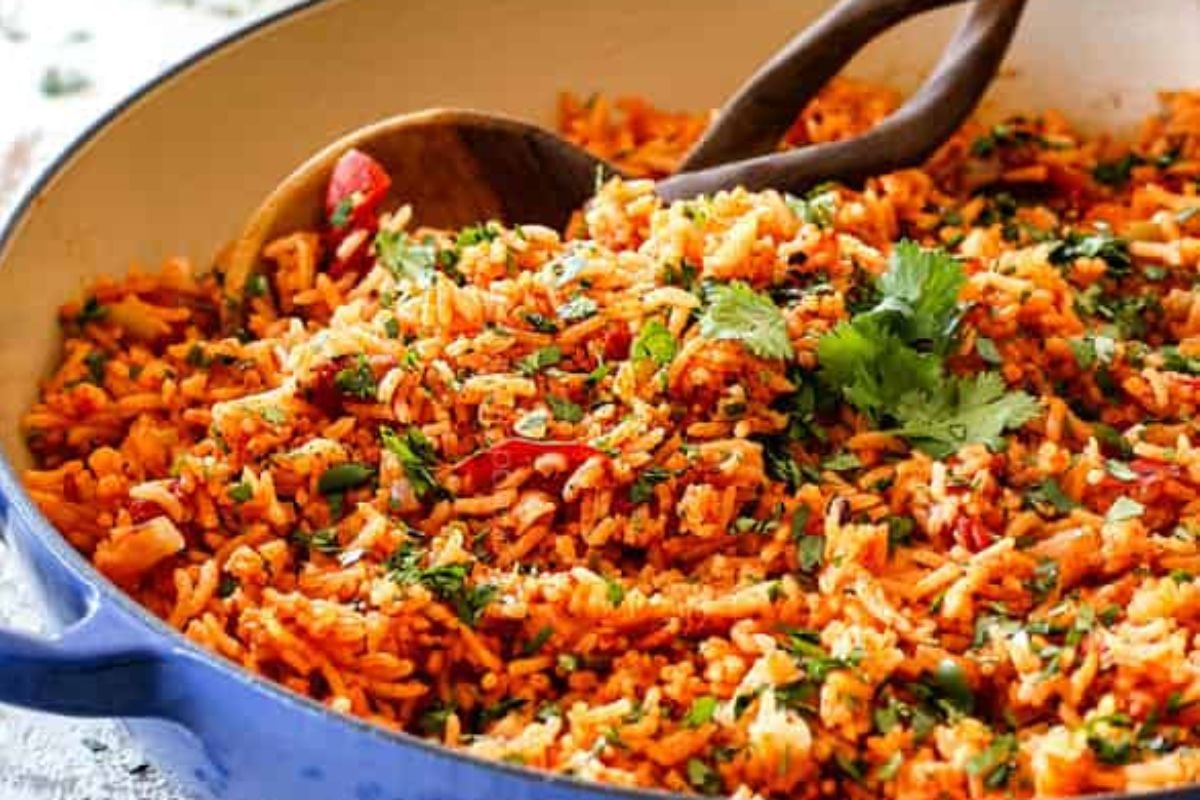 A bowl of rice with frozen vegetables and wooden spoons.