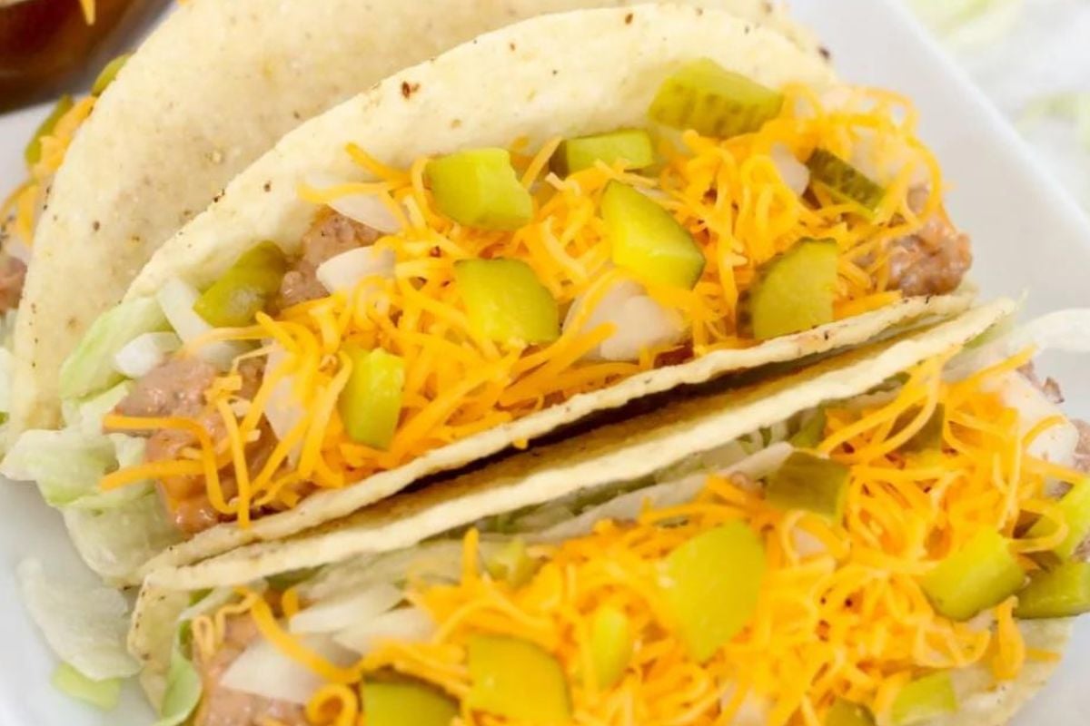 Two hard-shell tacos filled with shredded lettuce, cheese, onions, pickles, and a meat or bean mixture—perfect for fans of creative ketchup recipes.