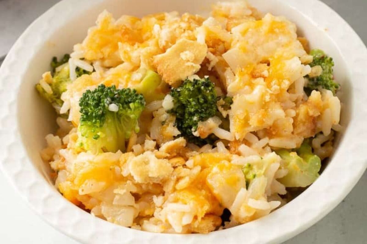 A bowl of broccoli and cheddar cheese casserole with a can of cream soup and cracker topping, served over rice.