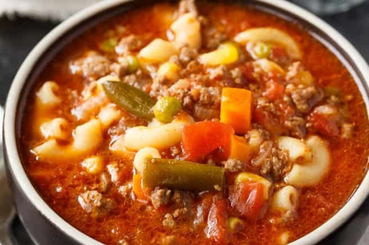 Close-up of a bowl of hearty vegetable beef soup with macaroni, ground beef, and mixed vegetables, made easily by using frozen vegetables.
