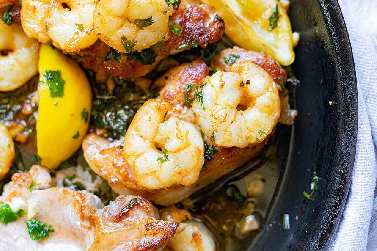 Close-up of sautéed shrimp and sliced lemon in a skillet, garnished with pork chop recipes.