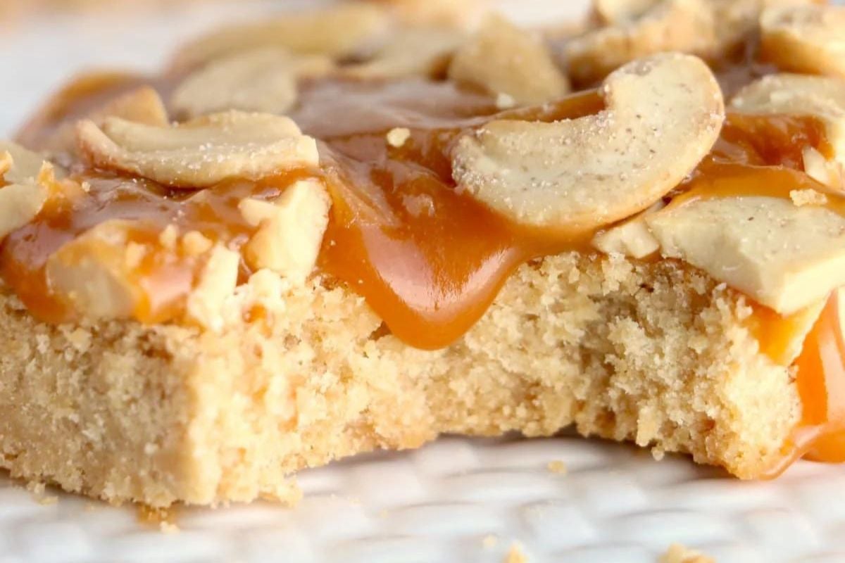 A close-up of a blondie dessert bar from our caramel recipes, topped with caramel sauce and sliced almonds.