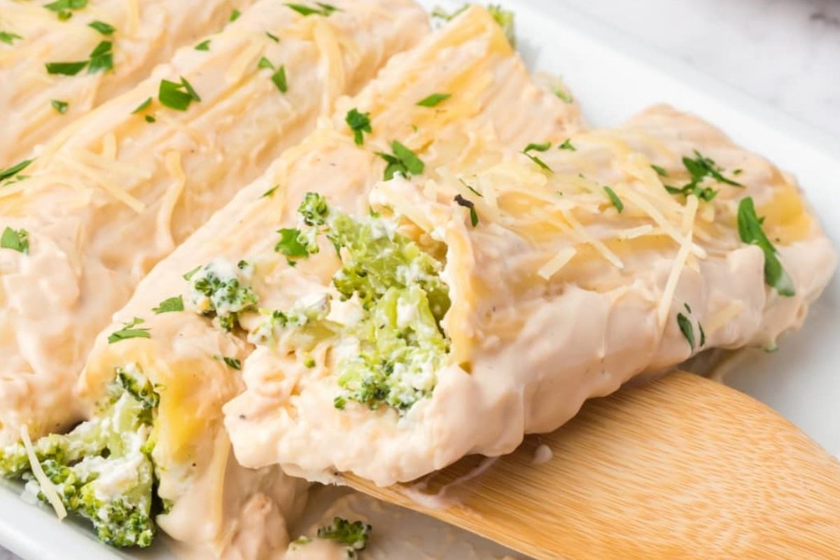 Chicken and broccoli cheese casserole on a serving dish with a wooden spatula.