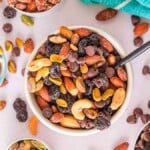 Three bowls of a homemade chocolate cherry trail mix on a light surface.