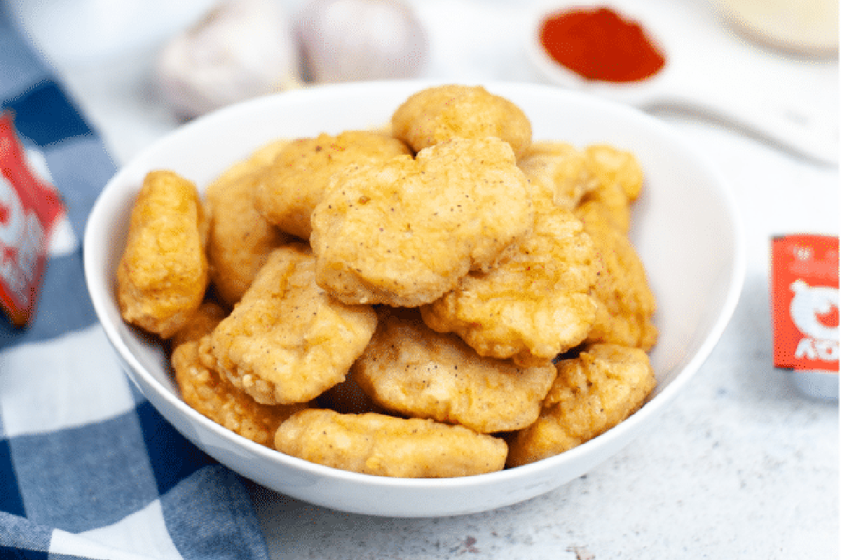 A bowl of McDonald's chicken nuggets with condiments in the background.